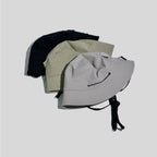 Packable nylon bucket hats in black, khaki green and light grey, loosely stacked to show their flexible construction