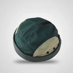 Panelled docker cap in forest green and beige, top view showing stitched crown seams, metal eyelets and a checked cuff