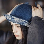 Woman adjusting a navy corduroy cap with a blue patchwork patterned under-brim