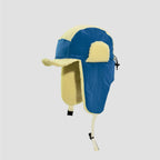 Blue and yellow plush-lined trapper hat side view with curved brim, long neck flap and contrast fuzzy ear panel.
