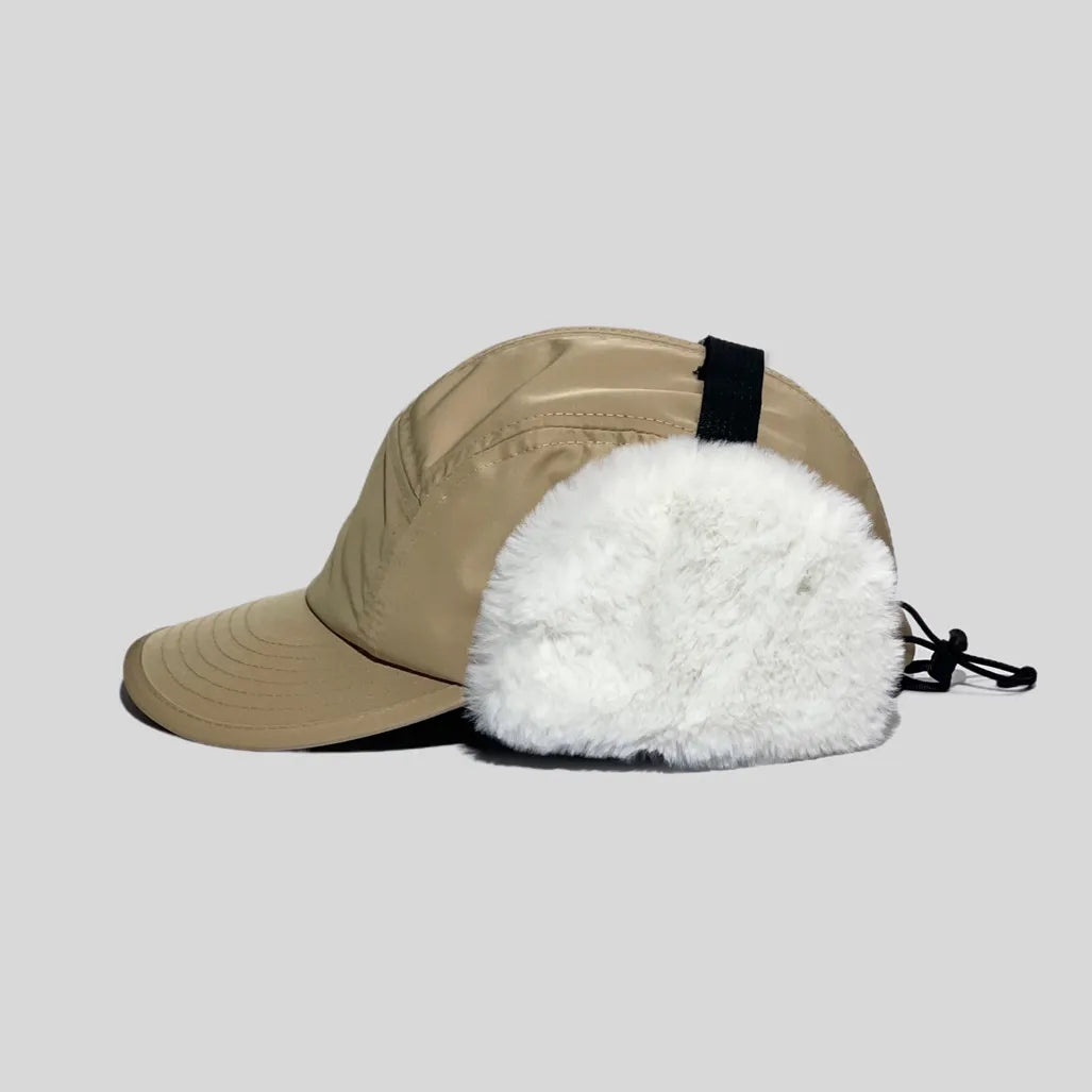 Polyester trapper cap in khaki, side profile with a curved peak, white faux-fur ear flap and rear cord lock

