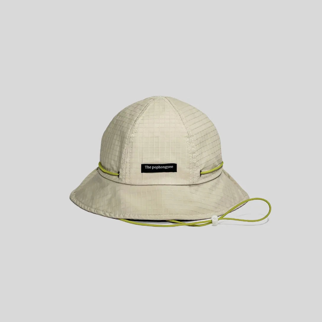 Quick-dry bucket hat in off-white with a lime green cord, front view showing the logo tab, grid weave and wide brim