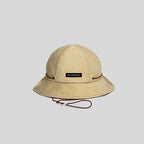 Quick-dry bucket hat in sand beige with a brown cord, front view showing the logo tab, grid weave and wide brim