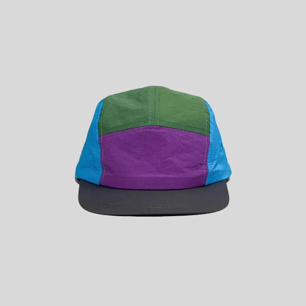 Quick-dry colour-block cap in green, purple and blue, front view showing the low crown and charcoal peak