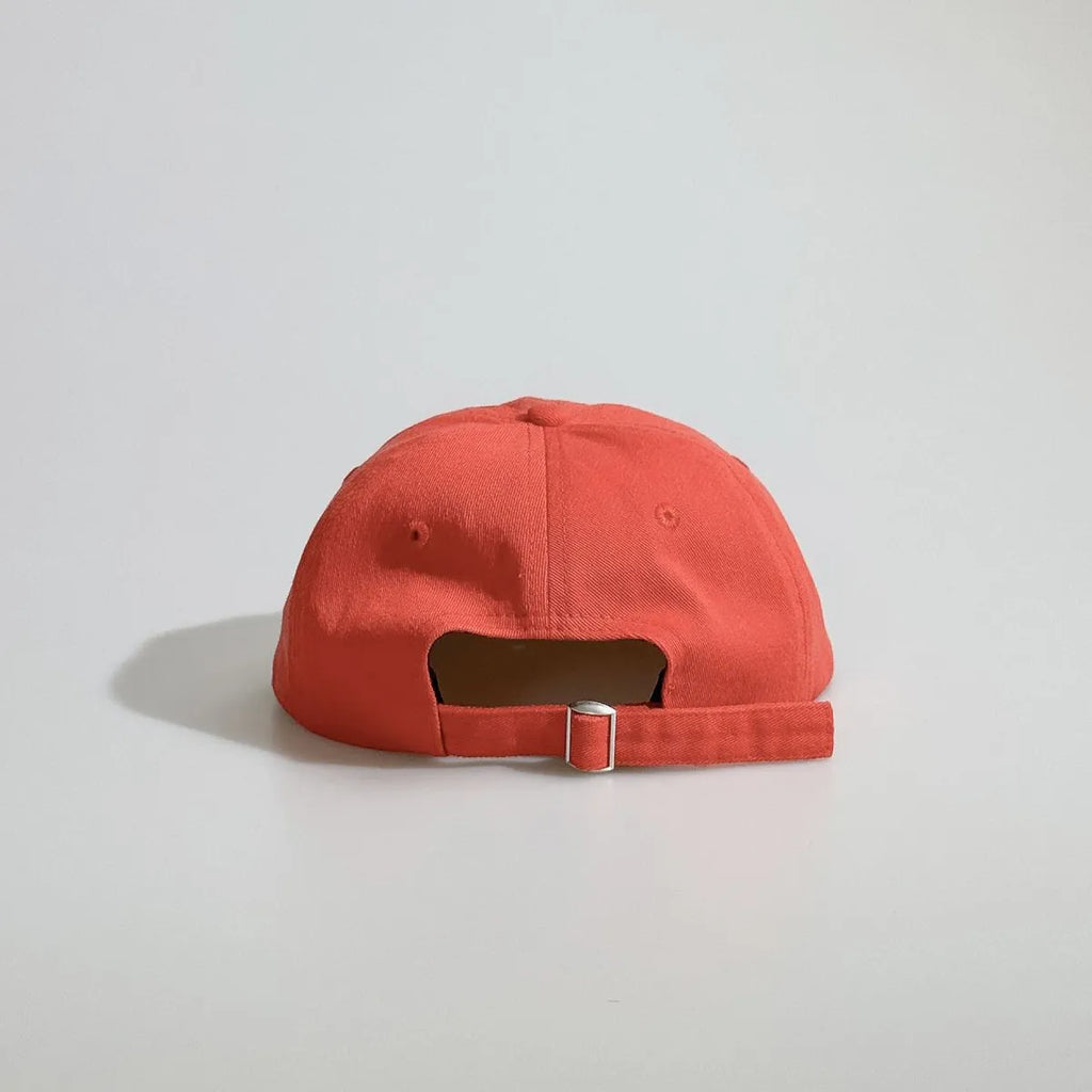 Back view of a red baseball cap with an open back, ventilation eyelets and an adjustable metal buckle strap.
