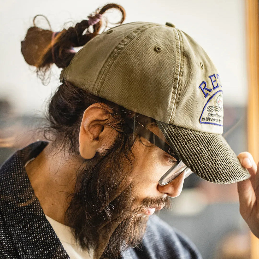 Retro embroidered baseball cap worn with glasses and a casual layered outfit in an indoor setting