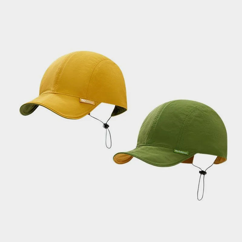 Mustard yellow and olive green reversible nylon cap shown from both colour sides, with a short curved peak and rear toggle.