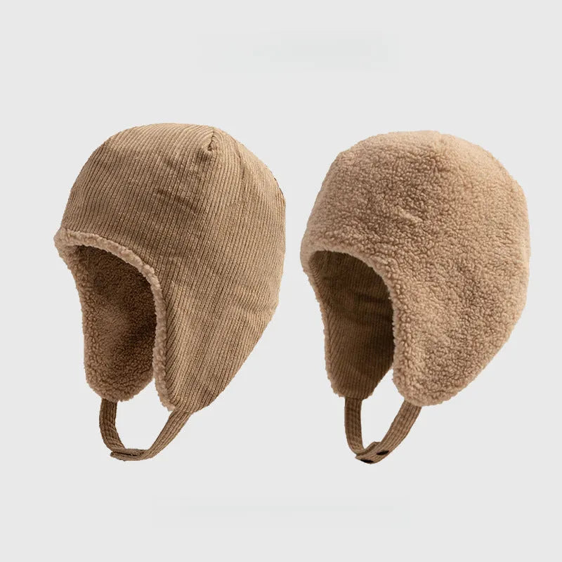 Beige reversible trapper hat shown with corduroy and teddy fleece sides, ear flaps and press-stud straps.