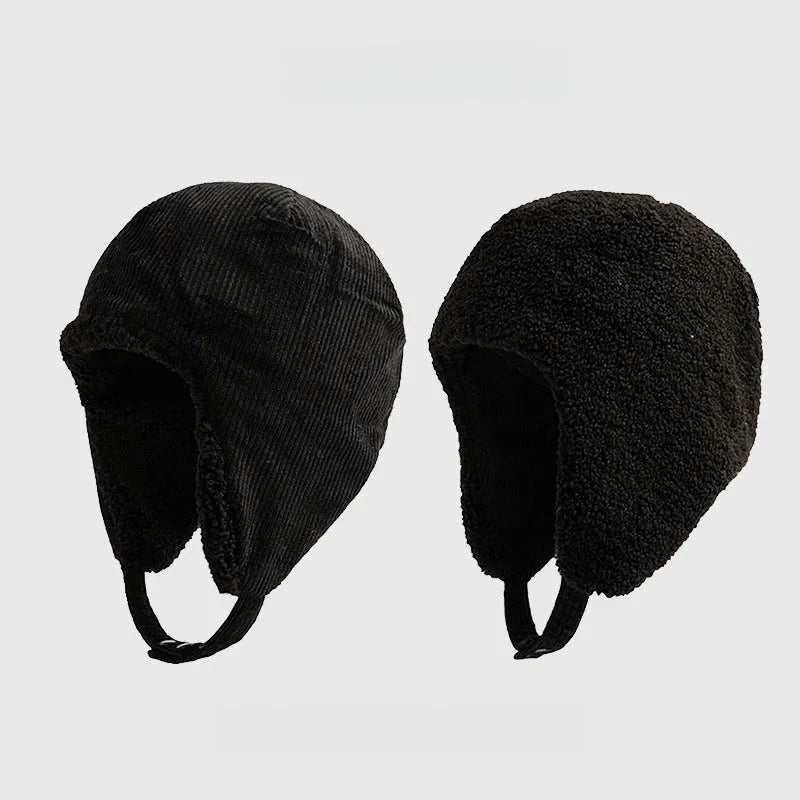 Black reversible trapper hat shown with corduroy and teddy fleece sides, ear flaps and press-stud straps.
