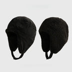 Black reversible trapper hat shown with corduroy and teddy fleece sides, ear flaps and press-stud straps.