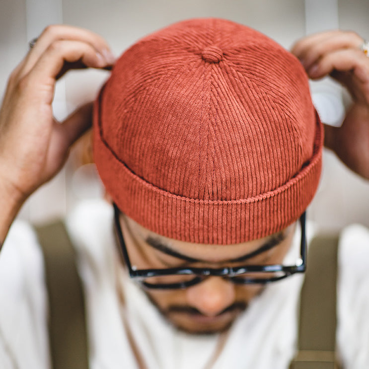 Top view of a rust cotton corduroy docker beanie showing the ribbed panels and rounded crown