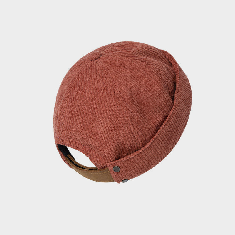 Rear view of a rust brown cotton corduroy docker cap with ribbed texture, rolled edge, brown adjustable strap and metal snap details