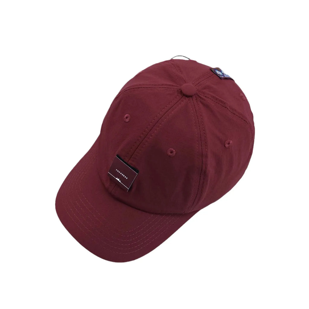 Six-panel baseball cap in burgundy, top view showing stitched seams, ventilation eyelets and a woven front label