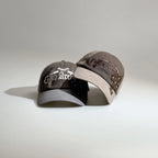 Grey and brown two-tone embroidered baseball caps with gothic graphics, curved brims and adjustable fits.