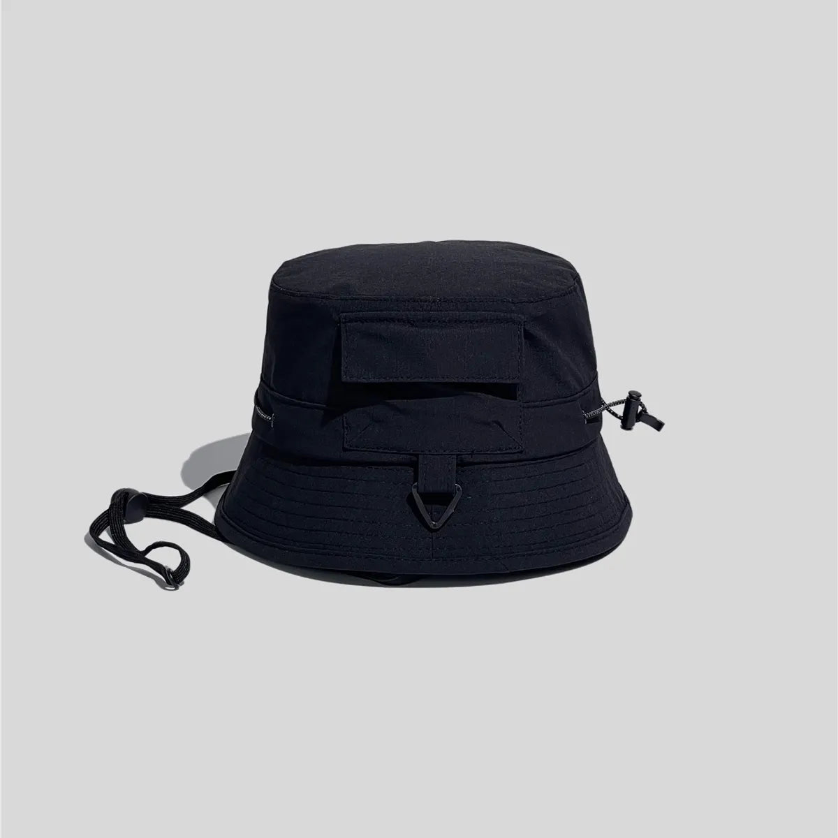 Utility bucket hat in black, side view showing the flap pocket, D-ring loop and adjustable crown cord