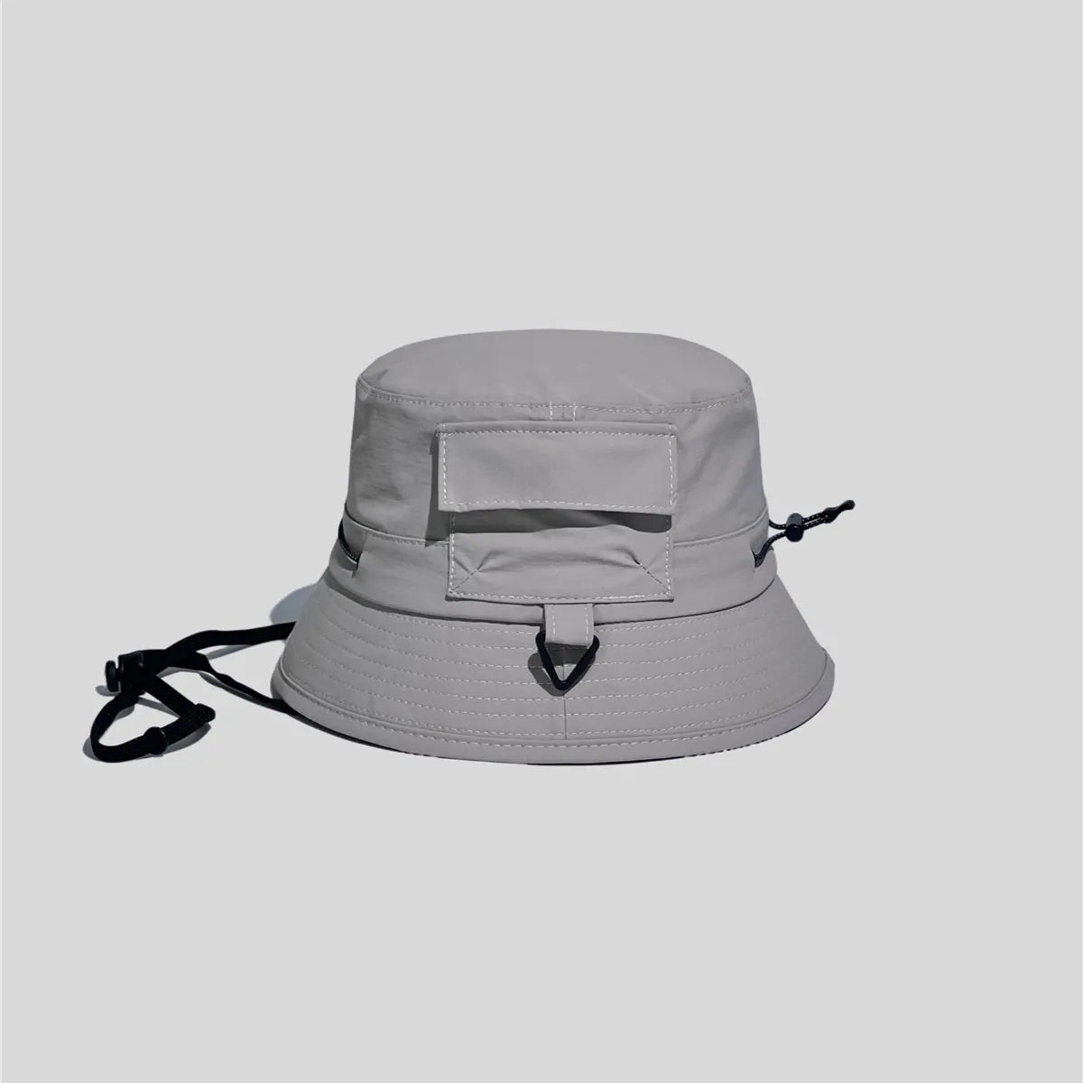 Utility bucket hat in light grey, side view showing the flap pocket, D-ring loop and adjustable crown cord