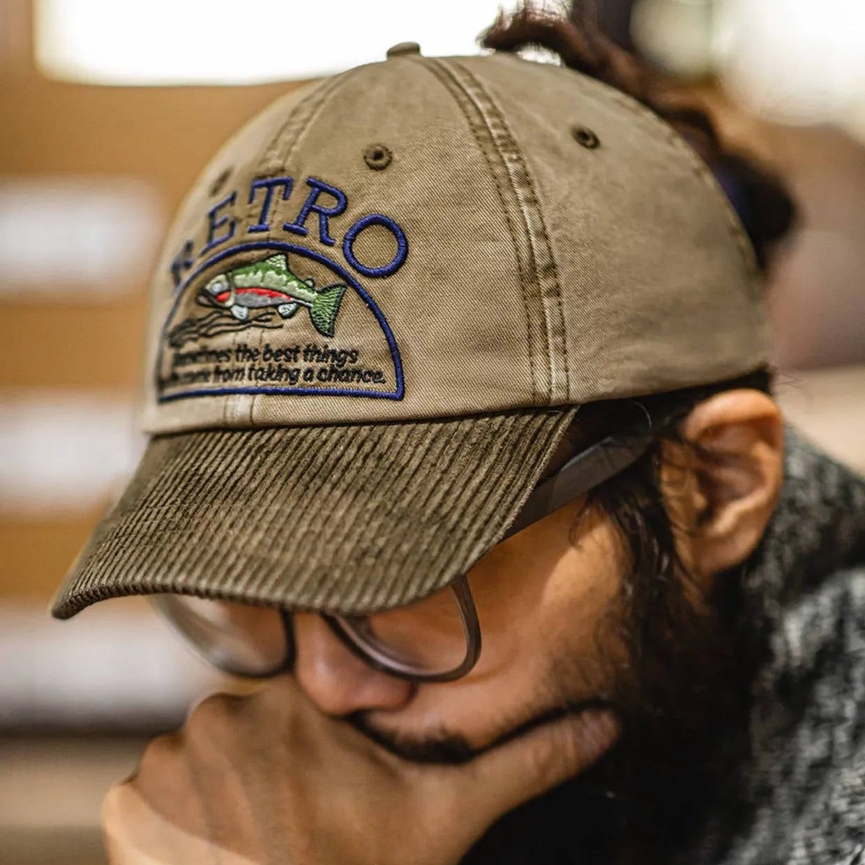 Man wearing a vintage cotton dad hat with a fish embroidery design and olive corduroy brim