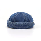 Brimless denim cap in washed indigo blue, side angle showing a rounded crown, rolled edge and pale topstitching