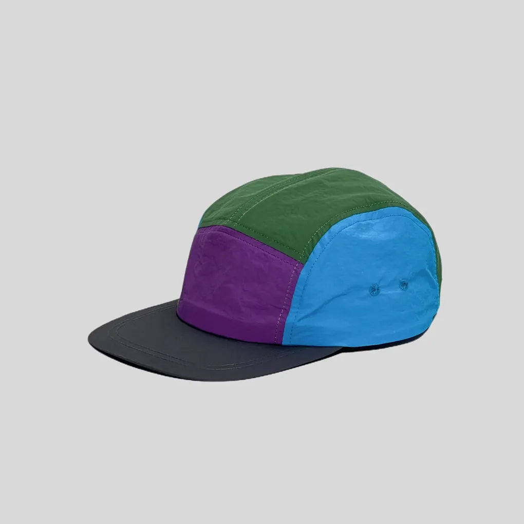 Waterproof 5-panel cap in green, purple and blue, side view with colour-block panels, twin eyelets and charcoal peak