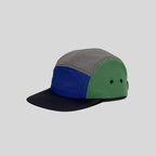 Waterproof 5-panel cap in grey, royal blue and green, side view with colour-block panels, twin eyelets and navy peak