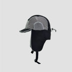 Black and grey waterproof trapper hat side view showing ripstop-style panels, plush ear detail and chin strap.