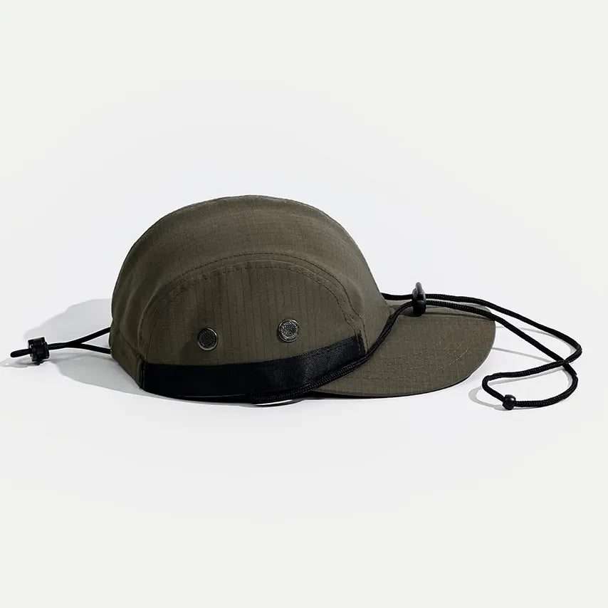 Waterproof outdoor cap in olive green, side view with two metal eyelets, black webbing trim and an adjustable cord