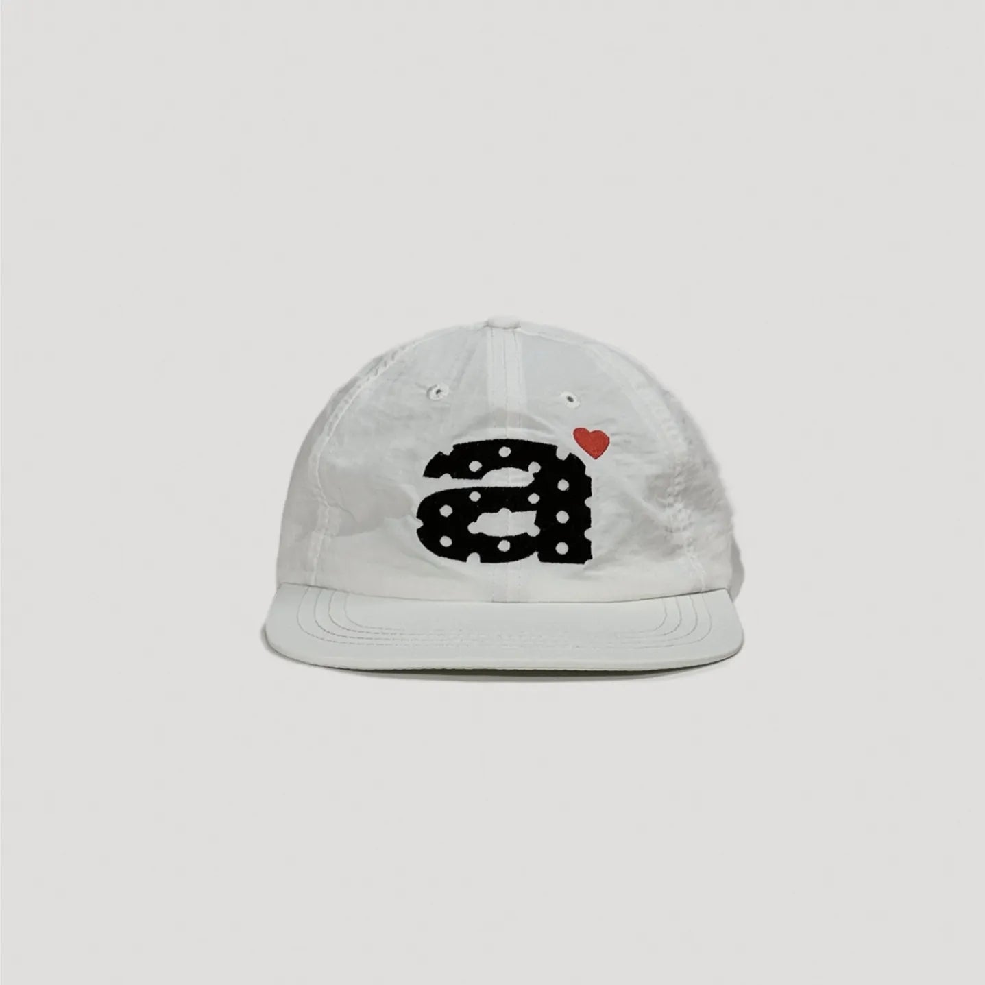 White nylon camp cap featuring bold embroidered graphic and minimalist streetwear look