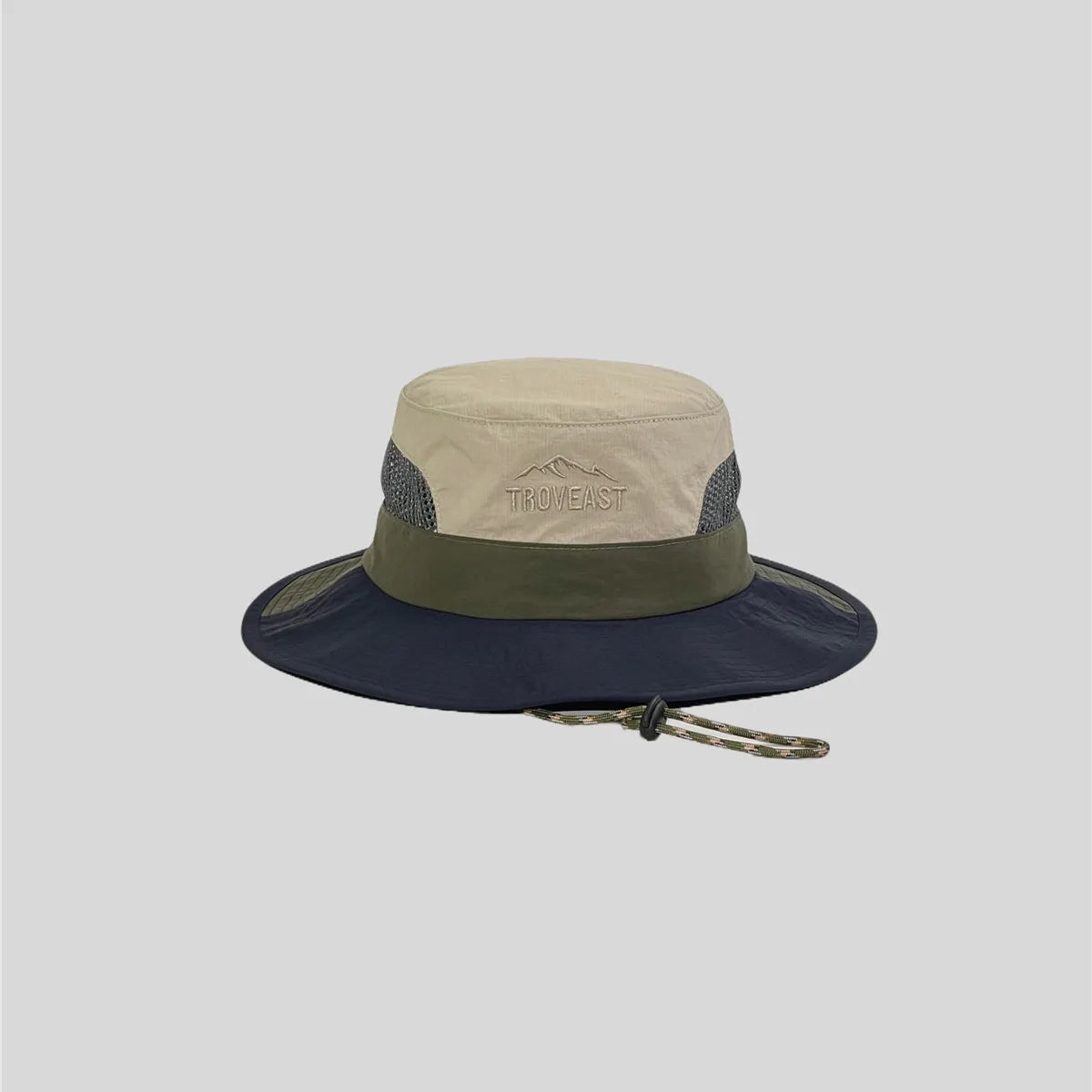 Beige wide-brim sun hat front view with olive band, navy brim, grey mesh panels and tonal mountain embroidery.