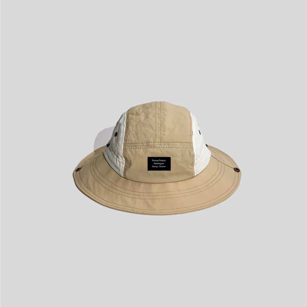 Beige wide-brim sun hat with white side panels, front patch label, stitched brim and metal snap fasteners.