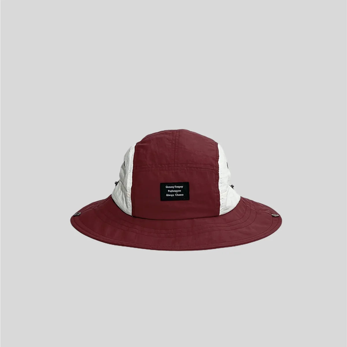 Burgundy wide-brim sun hat with white side panels, front patch label, stitched brim and metal snap fasteners.