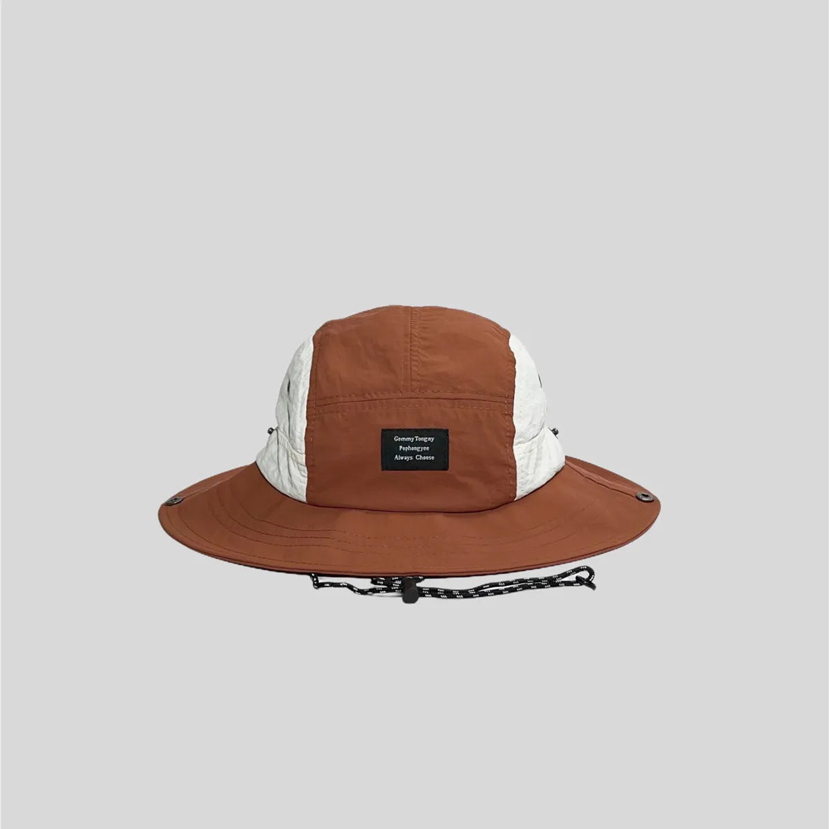 Rust orange wide-brim sun hat with white side panels, front patch label, stitched brim and metal snap fasteners.