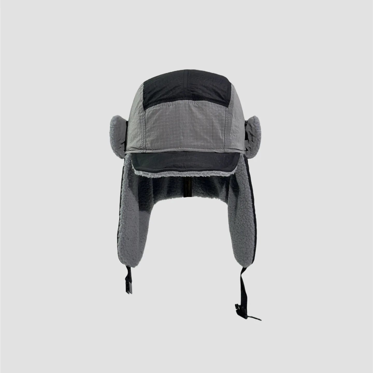 Black and grey windproof trapper hat front view with curved brim, long ear flaps and soft plush inner edges.