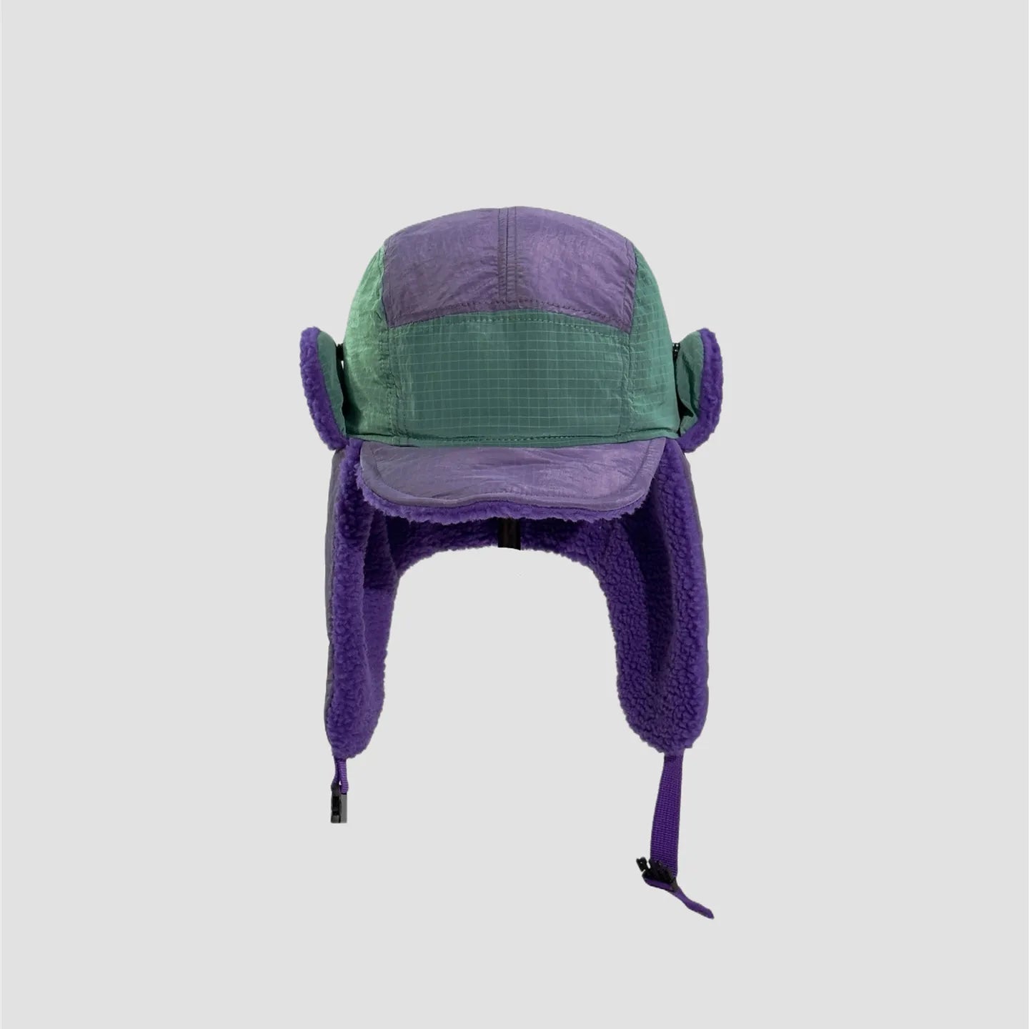 Green and purple nylon ear flap hat front view with colour-block panels, curved brim and plush ear coverage.
