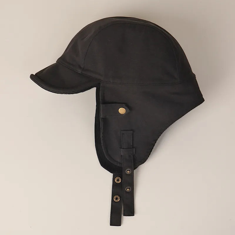 Black winter ear flap cap in side view with a curved short brim, long side panels and snap straps.