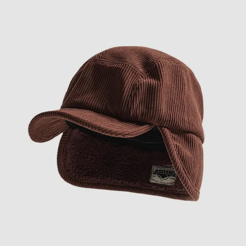 Chestnut winter ear flap cap featuring a curved peak, ribbed outer texture and warm fold-down ear panels.