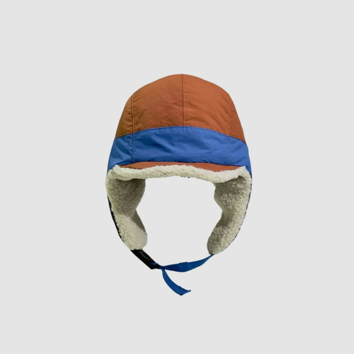 Orange and blue winter trapper cap front view with cream fleece ear flaps, curved peak and chin strap.