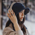 Woman styling a navy corduroy ear flap cap with headphones and a casual sweatshirt