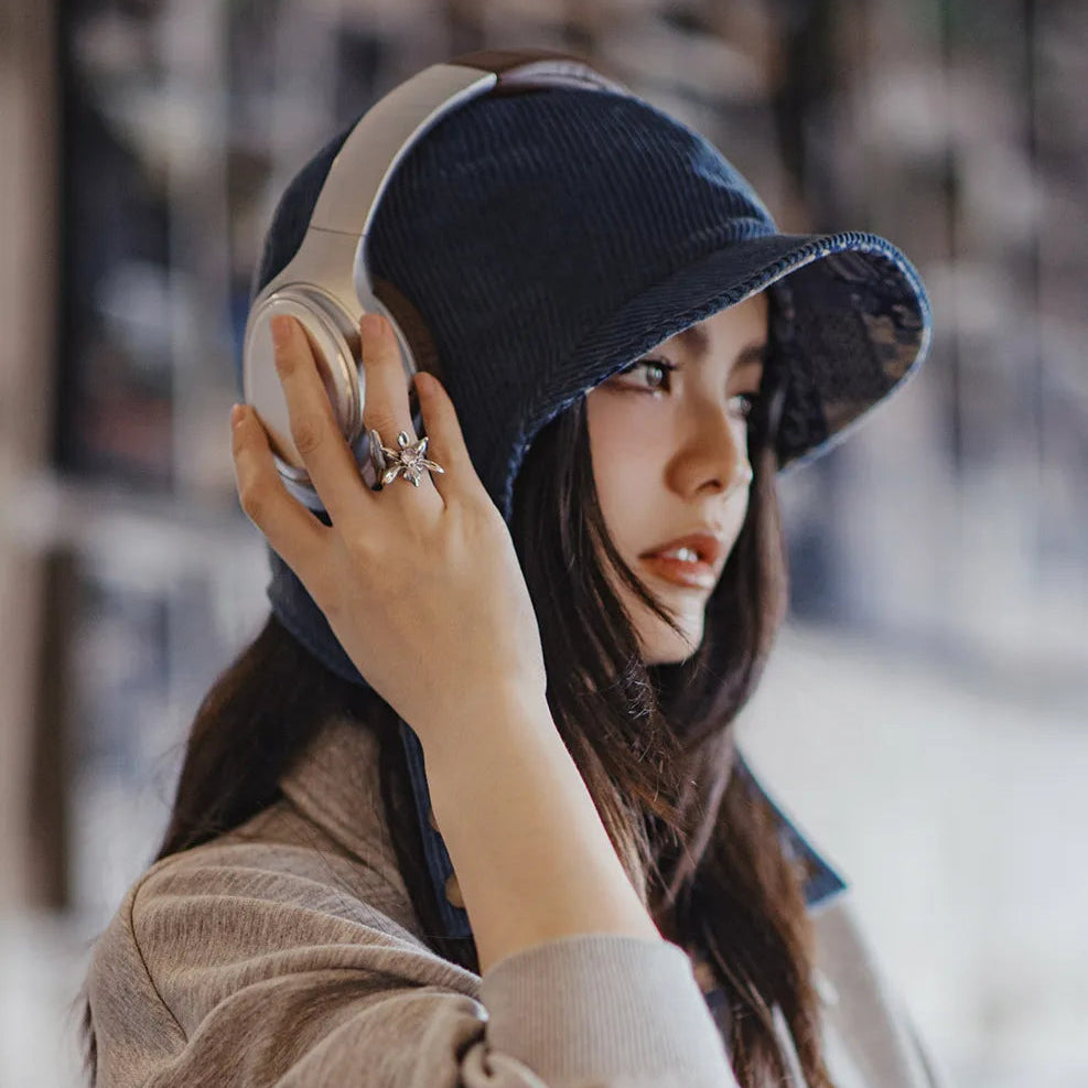 Woman styling a navy corduroy ear flap cap with headphones and a casual sweatshirt