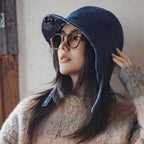 Woman wearing a navy cotton corduroy ear flap baseball cap with a curved brim and side straps